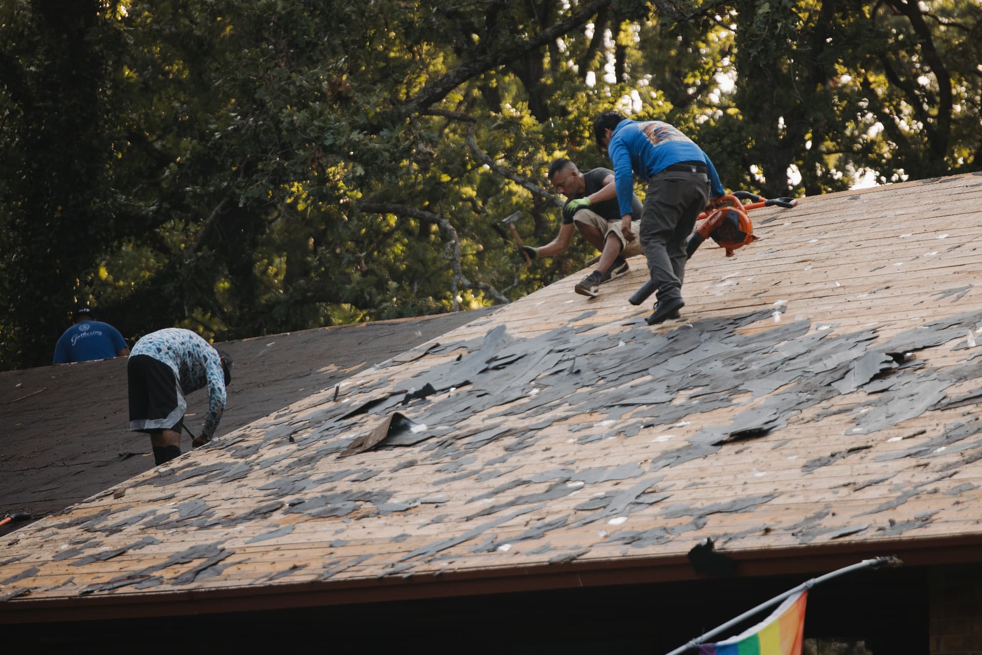 Crew members stripping shingles down to the decking