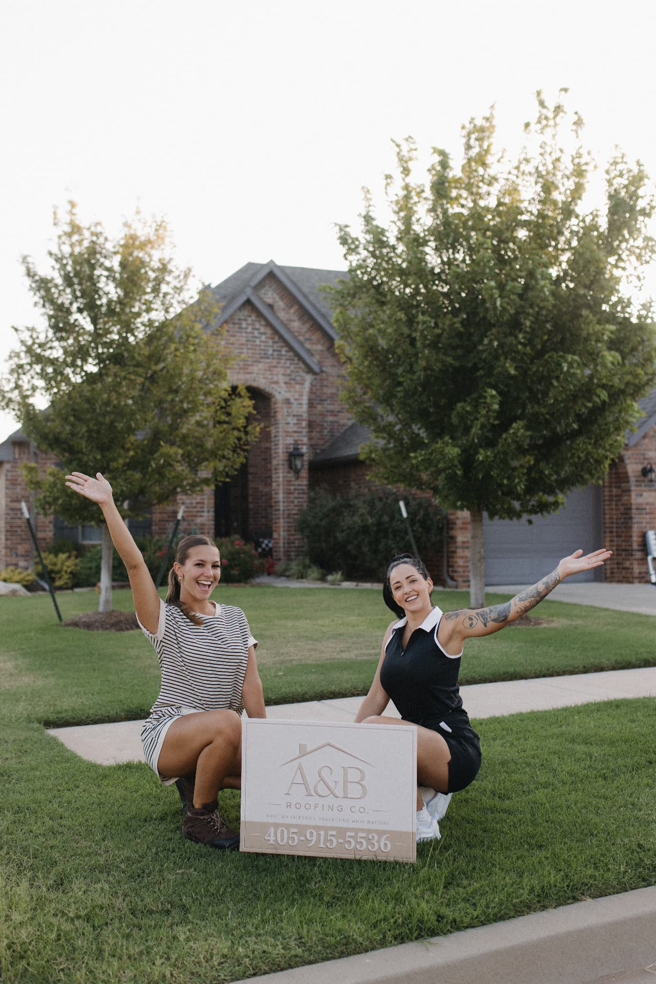 Ameilla and Brooklynn beside an A & B Roofing yard sign