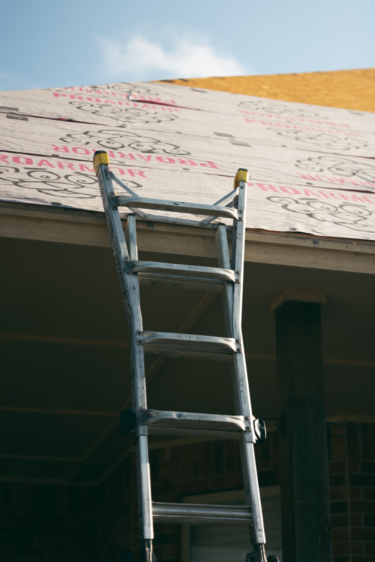A ladder resting against the eave of a wrapped roof