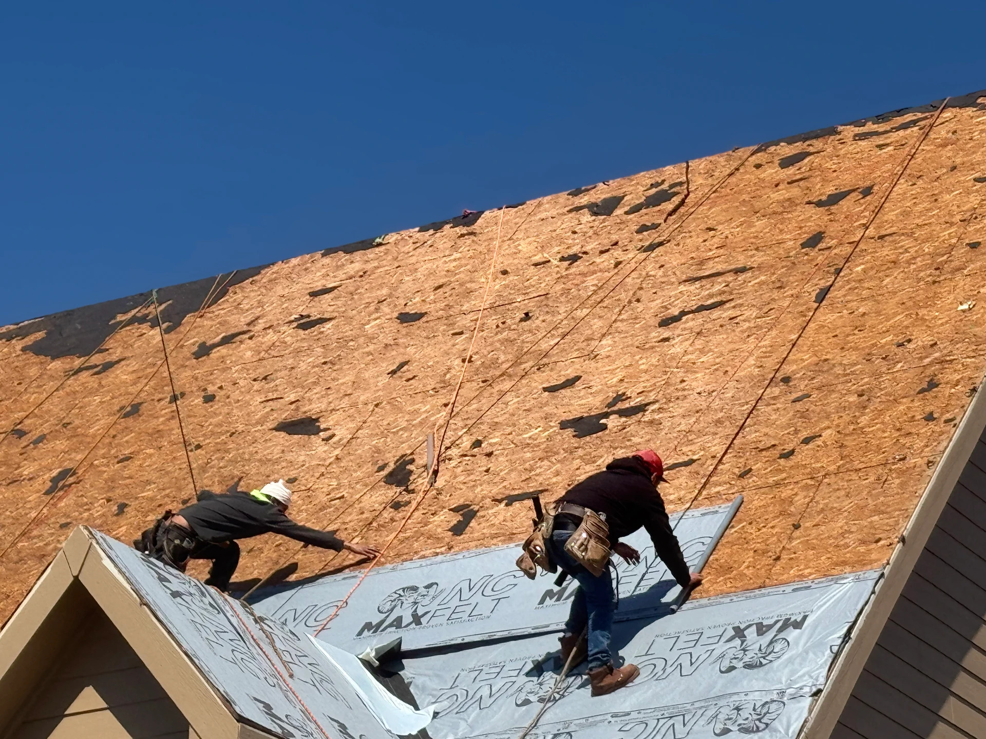 Two crew members climbing fresh decking against a blue sky