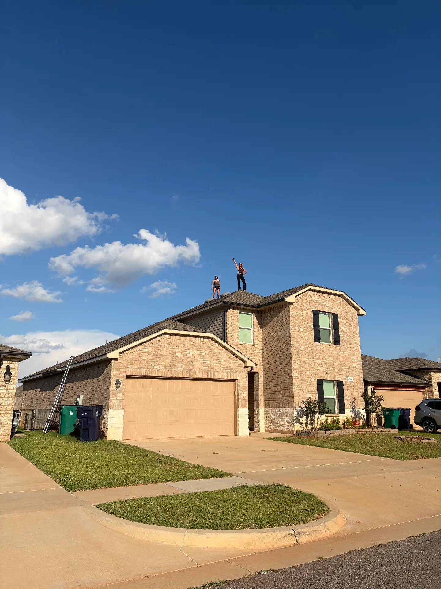 Two team members standing on the peak of a brick home