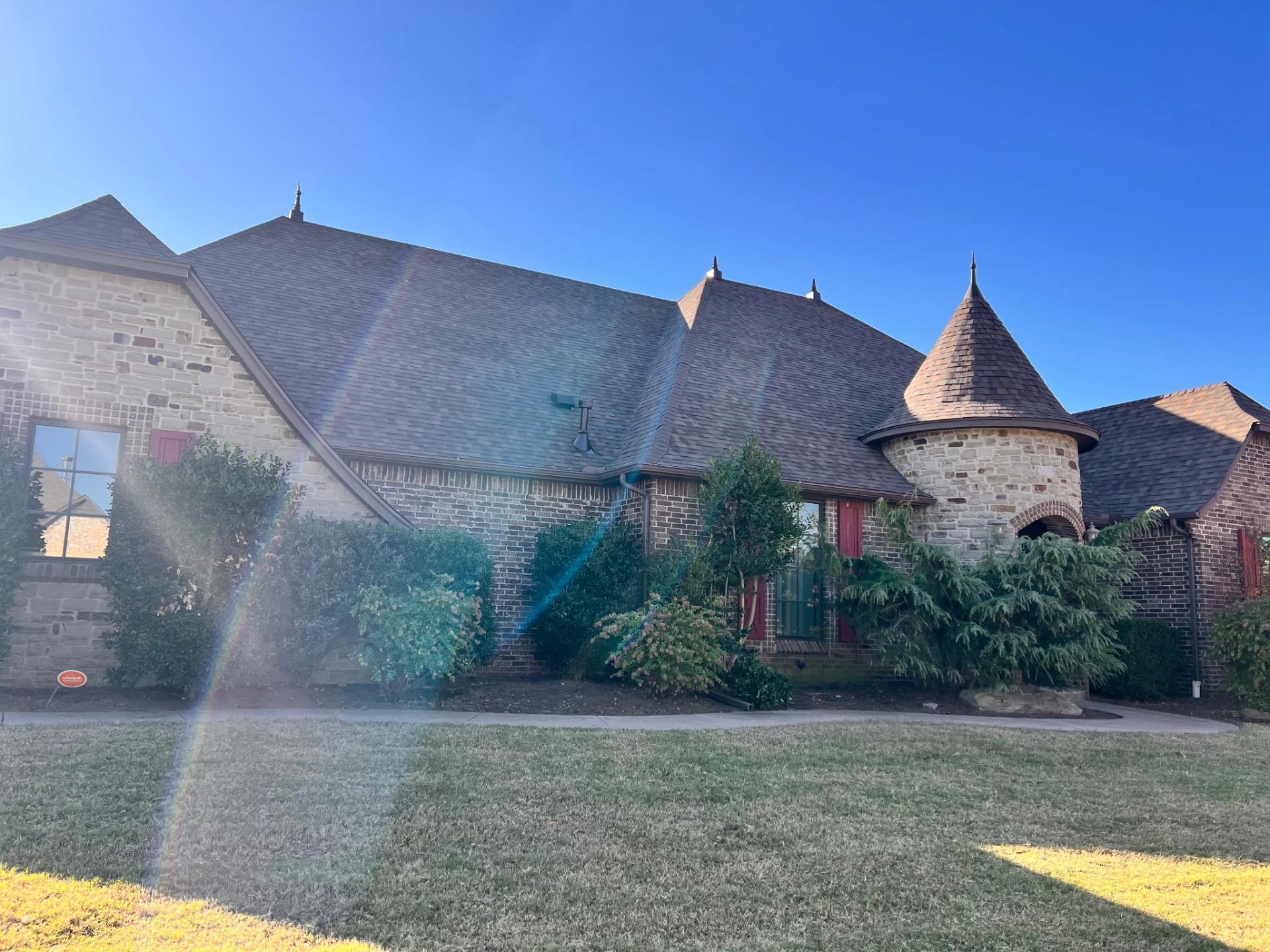 A stone home with a turret and a fresh shingle roof