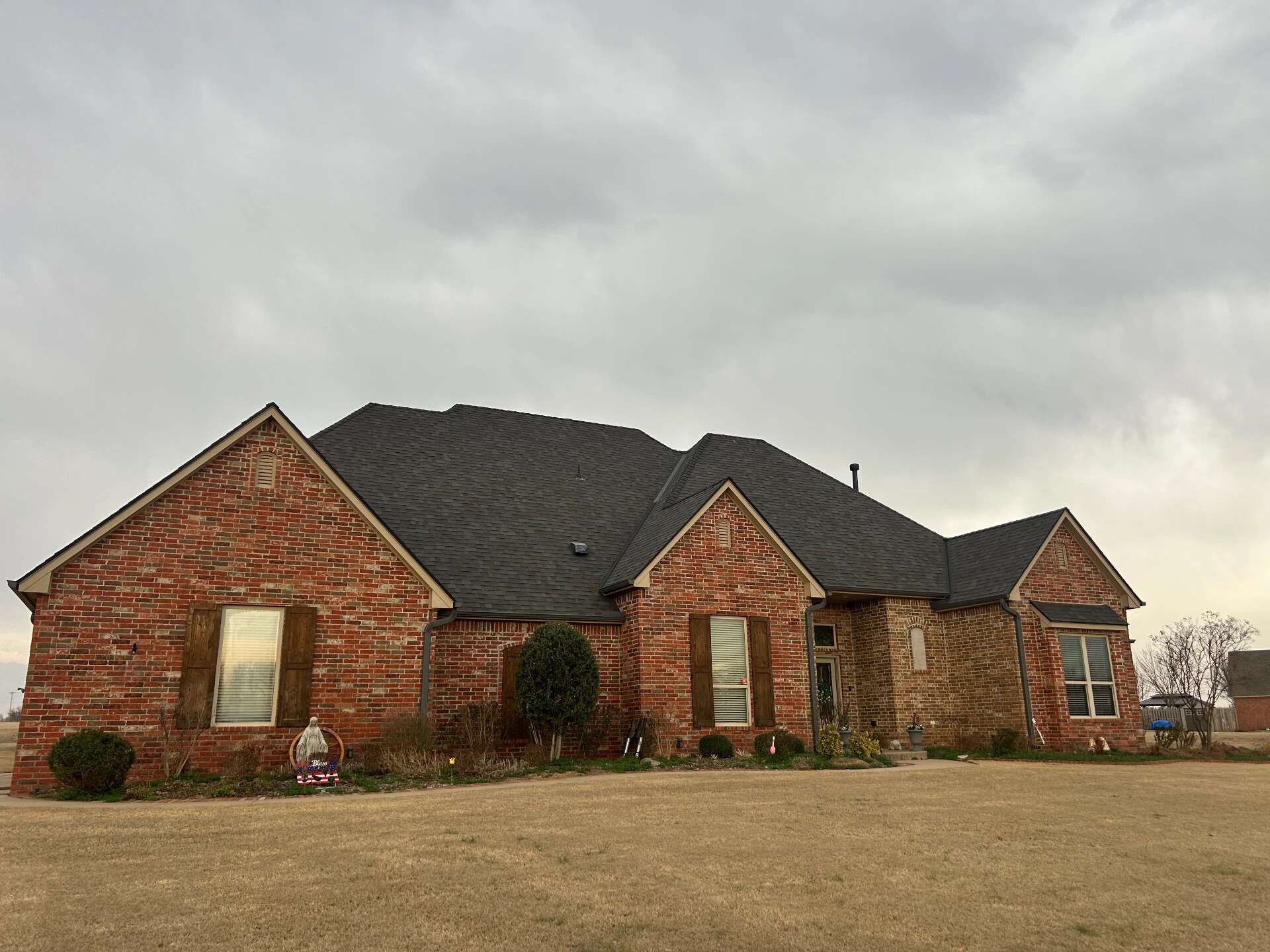 A brick home with a fresh roof under an overcast sky
