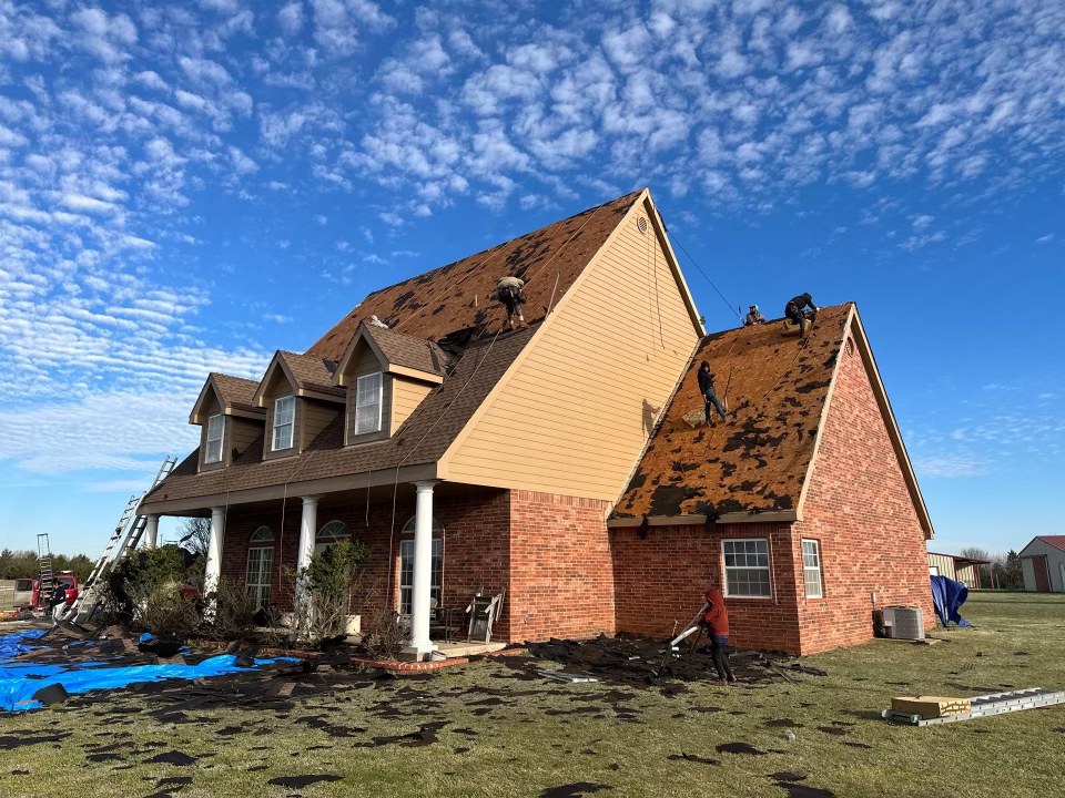 A crew stripping a steep gable roof down to the decking