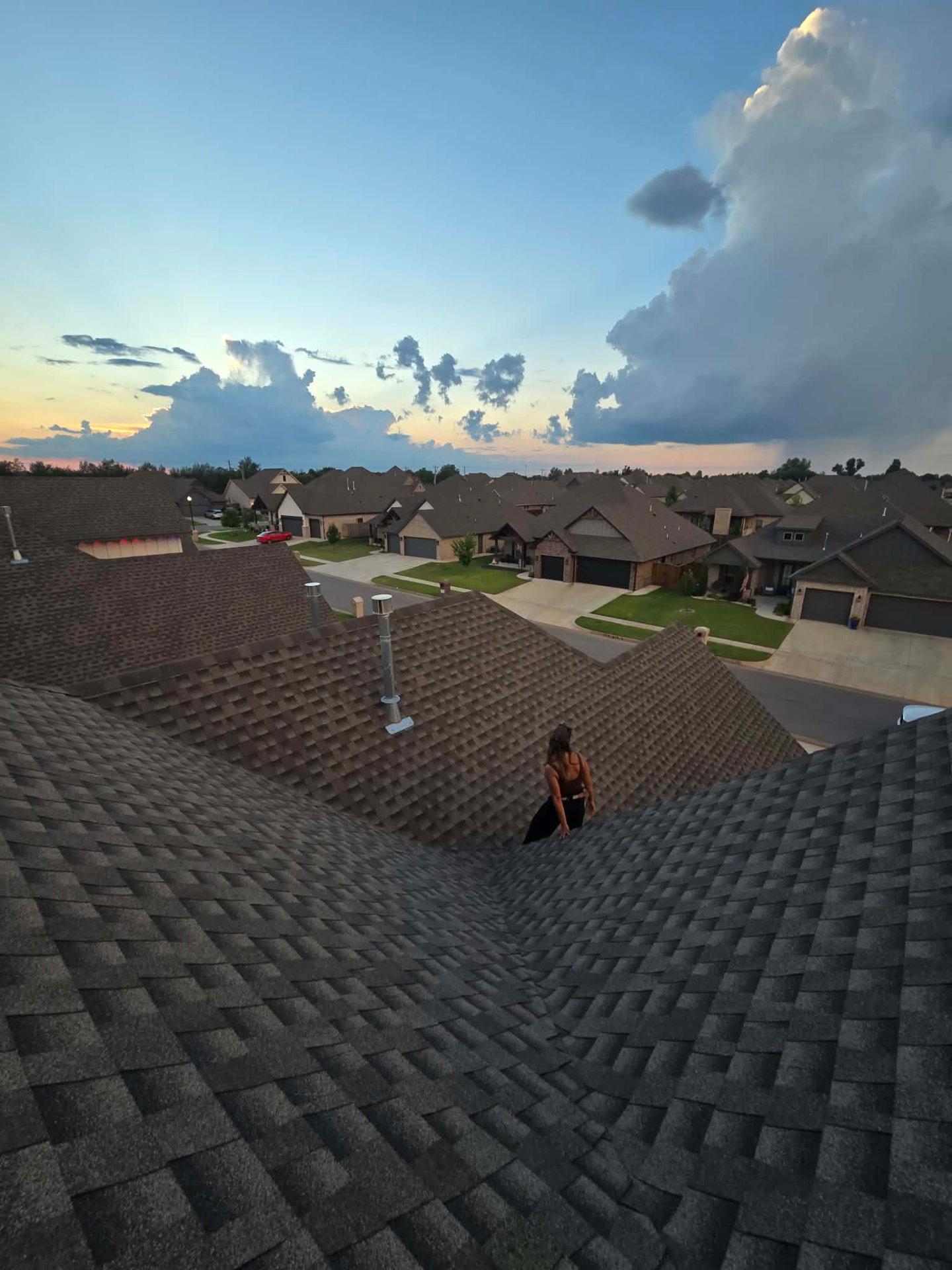 Walking a roof ridge at dusk over the neighborhood