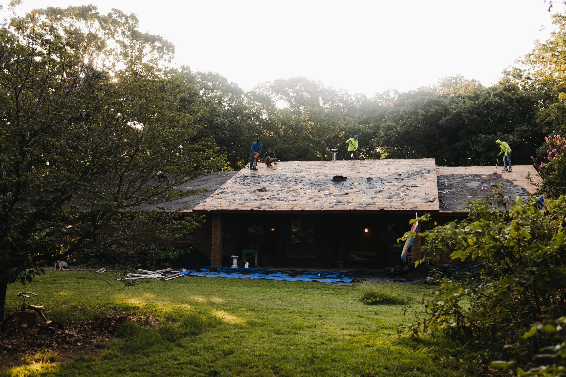A crew working a full tear off on a home tucked in the trees