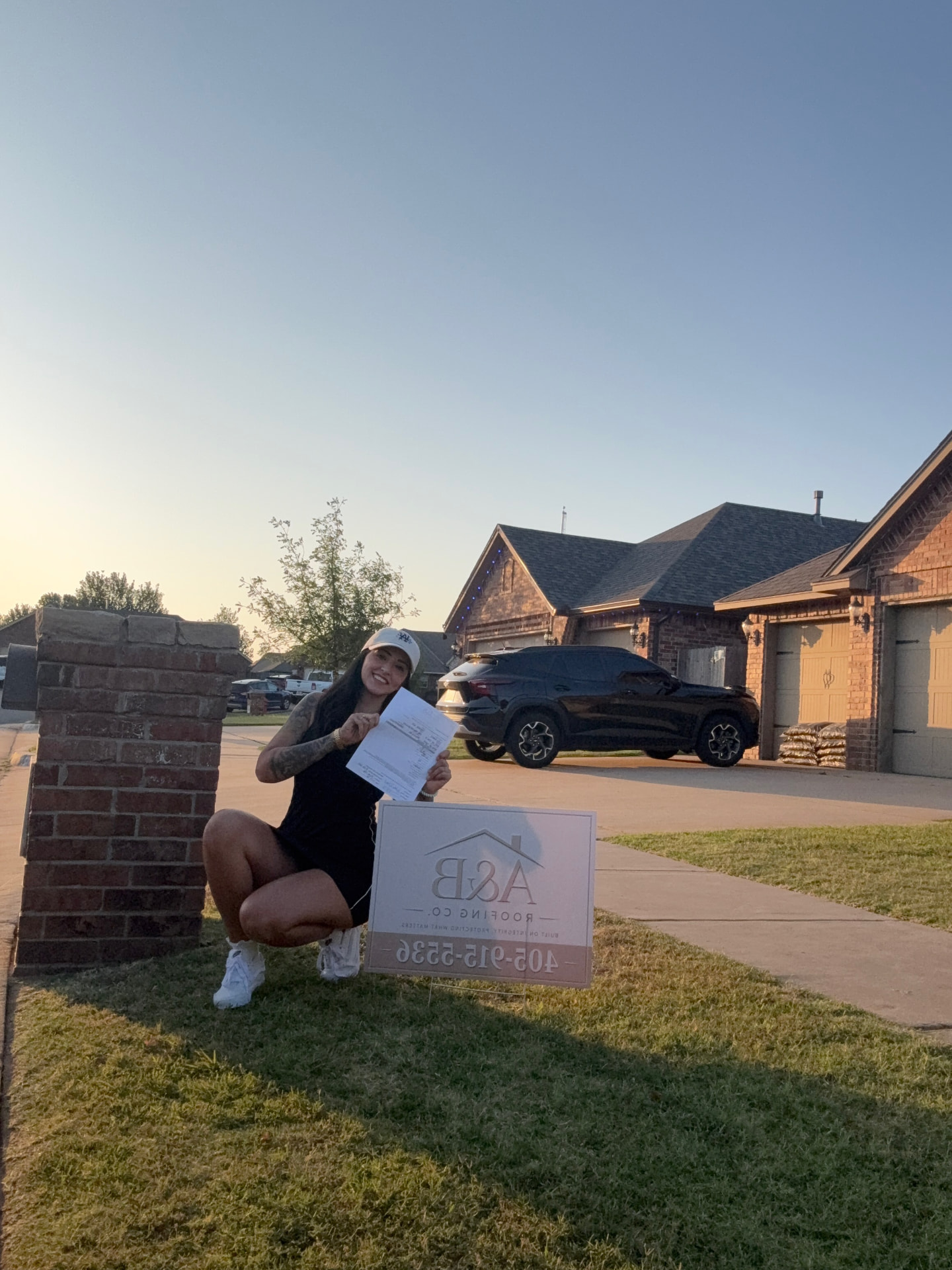 Holding an approved insurance claim in front of a client home